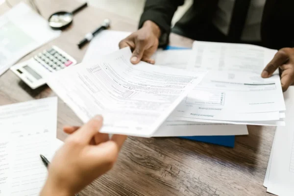 Intuition & Tarot: Trusting your inner voice - 9 Two professionals exchanging documents in an office setting, focusing on paperwork and data analysis.